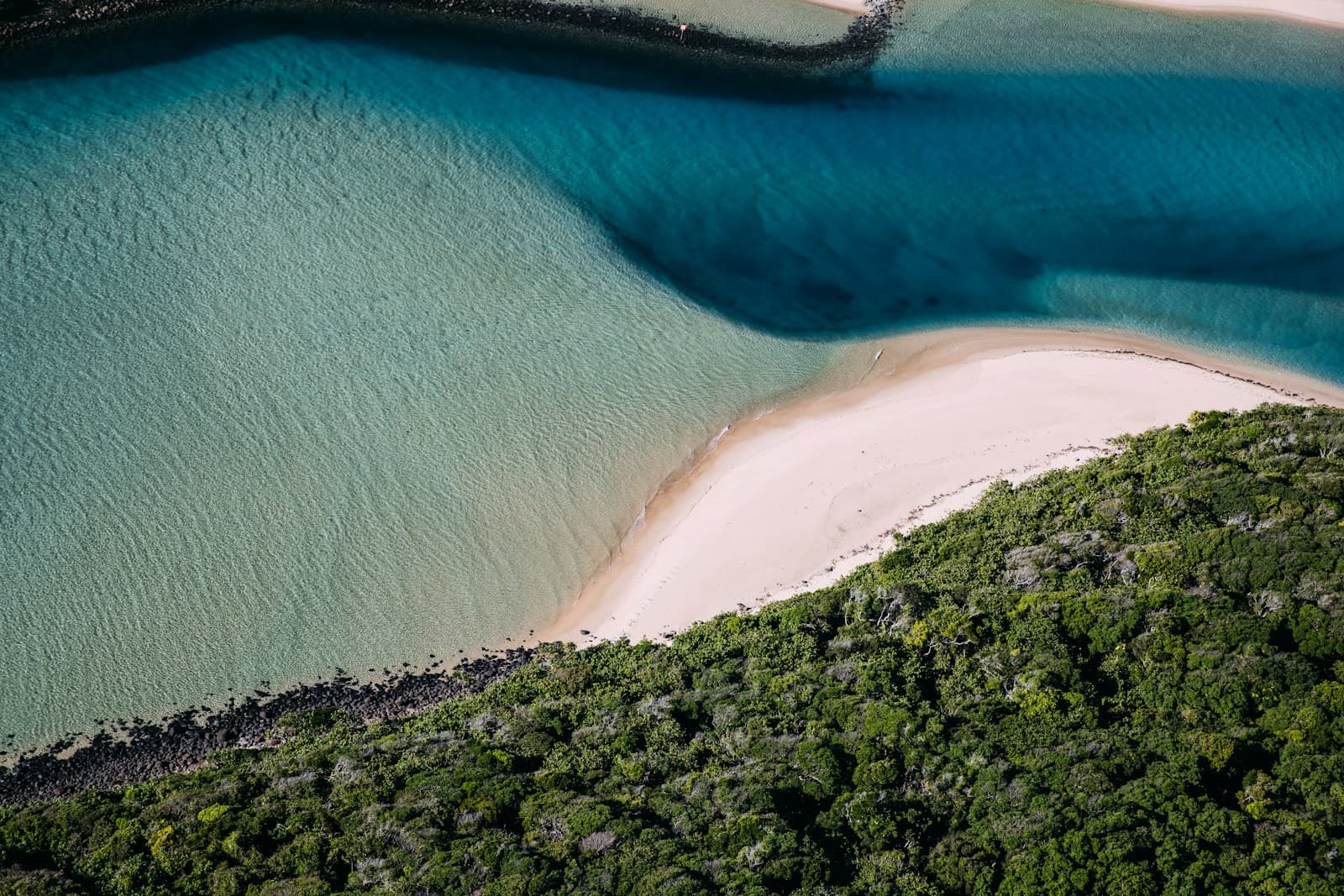 Aerial shot of Whitsunday Island looking south over Hill Inlet toward Whitehaven Beach, white swirling sandbar patterns visible, teal water, no boats in frame. Shot from a light aircraft in mid-morning light.