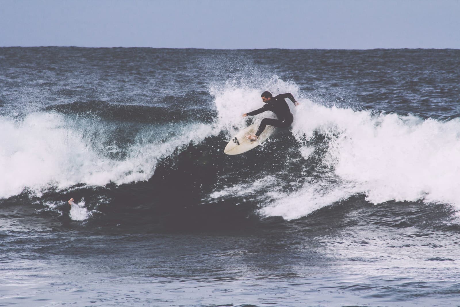 Beginner surfers paddling out at a sandy point break at golden hour, instructor in a rashie counting waves on the shoulder, soft glassy lines, northern NSW feel.